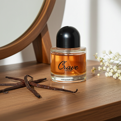 Crave hair and body mist bottle on a wooden surface with vanilla beans and flowers.